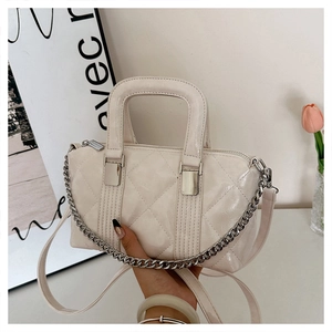 Detail of cream quilted pillow bag featuring silver chain and adjustable leather strap