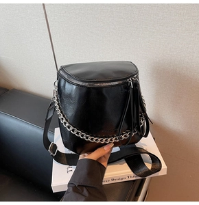 Detail of black saddle bag featuring silver chunky chain and adjustable wide strap