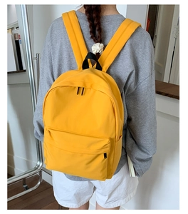 Rear view of a model wearing a bright yellow large-capacity backpack with black handle