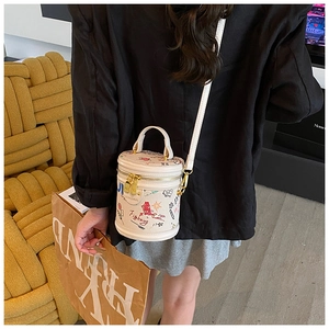 Detail shot of a white graffiti bucket bag worn crossbody against a yellow texture background