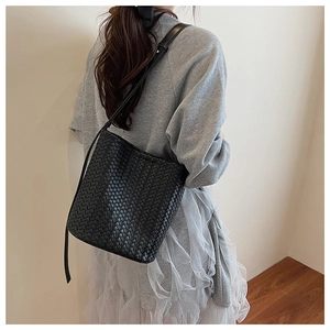 Detail of classic black woven bucket bag showing premium texture and slender leather strap