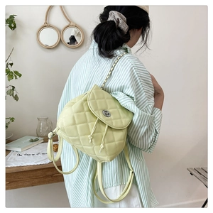 Detail of light green quilted leather backpack with chain strap and silver twist lock
