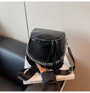 Close-up of black bucket bag featuring silver chain detail and wide nylon shoulder strap