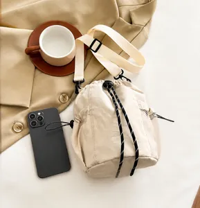 Close-up of beige nylon bucket bag with mesh side pocket and thick drawstring closure