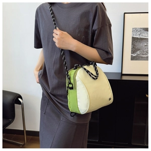 Detailed shot of green and beige crossbody bag with a striped woven rope strap