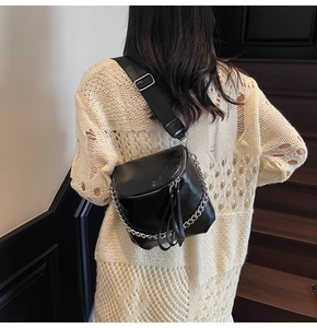 Detail of black glossy saddle bag featuring silver chain and wide webbing strap