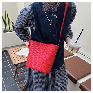 Vue détaillée du sac seau en cuir tressé rouge porté en bandoulière sur un modèle