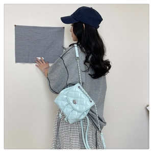 Quilted light blue leather backpack with silver chain strap shown on model side view