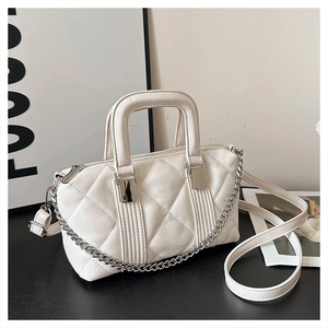 Close-up of white quilted PU leather handbag with silver chain and dual handles