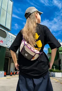 Outdoor street view of a trendy off-white crossbody sling bag with purple accents and red cords