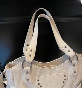 Détail de la bandoulière en cuir beige avec anneaux en métal et rivets en étoile