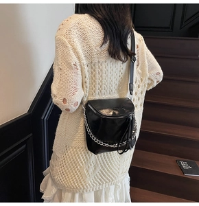 Detail of a black patent leather bucket bag with chunky silver chain and long tassel zip puller