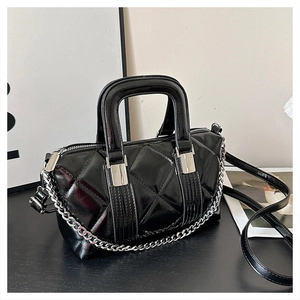Detailed view of black quilted faux leather handbag with silver chain and glossy finish