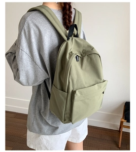 Side view of olive green canvas backpack on model showing large capacity and side pockets