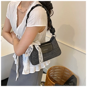 Close-up of black polka dot handbag with large white lace bow and woven handle detail
