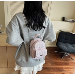 Detail of pink quilted mini backpack with silver chain strap and rhinestone studs
