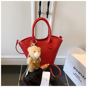 Détail du sac à main rouge texturé avec un charmant porte-clés ours en peluche