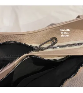 Gros plan du curseur de fermeture en métal lisse sur le sac à main en cuir beige