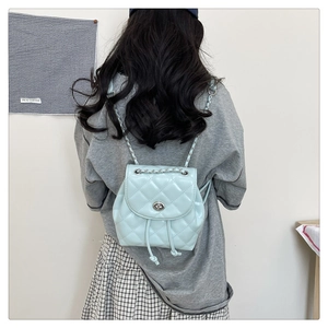 Detail of light blue quilted mini backpack featuring silver chain straps and turn-lock