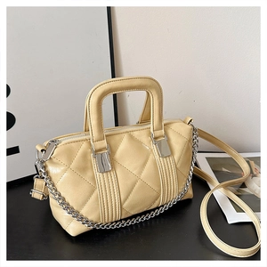 Detail of light yellow quilted tote bag with silver chain strap and metal hardware