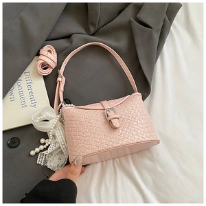 Détail du sac tissé rose avec breloque en perles et dentelle et bandoulière réglable