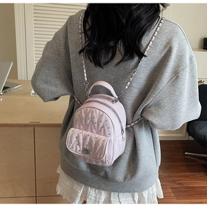 Close-up of pink quilted mini backpack with sparkling rhinestones and chain straps