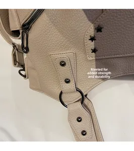 Détail du sac en cuir grainé avec rivets de renforcement, clous en étoile et anneaux noirs