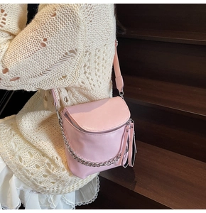 Detail of light pink leather saddle bag with silver chain and chic tassel decoration