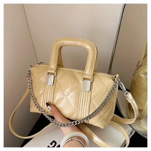 Detail of beige quilted boston bag with silver chain handle and glossy leather finish