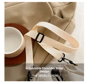 Detail of adjustable beige nylon shoulder strap with black buckle and metal swivel hook