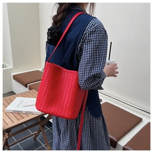 Detail of red woven leather bucket bag showing artisanal texture and crossbody strap