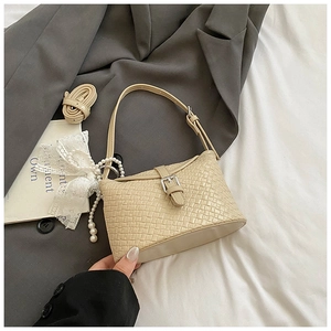 Détail du sac seau tressé beige avec fermoir en métal et breloque perle et dentelle