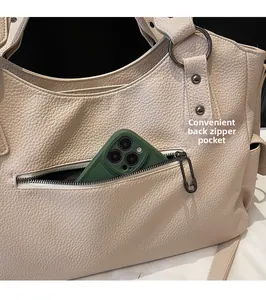 Détail de la poche zippée arrière d'un sac bandoulière beige en cuir avec des clous argentés