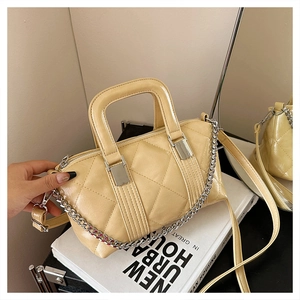 Close-up of beige quilted pillow bag with metallic chain strap and glossy finish