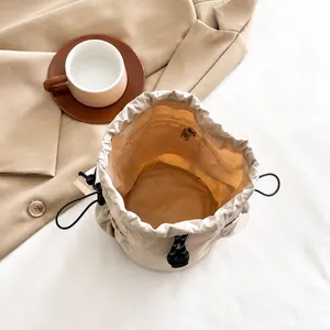 Internal view of beige nylon bucket bag featuring a zipper pocket and drawstring closure