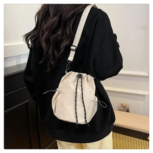 Detail der cremeweißen Nylon-Beuteltasche mit gewebtem Kordelzug und seitlichem Netzfach