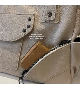 Détail de la poche zippée avant sur cabas en cuir beige avec rivets en étoile
