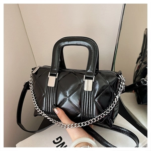 Detail of black quilted leather pillow bag with silver chain and glossy finish