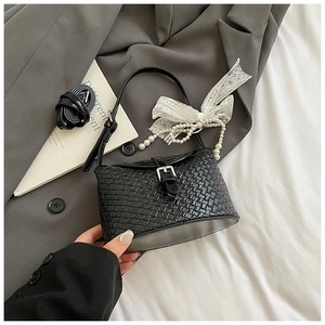 Détail du sac seau en cuir tressé avec boucle argentée et breloque en perles