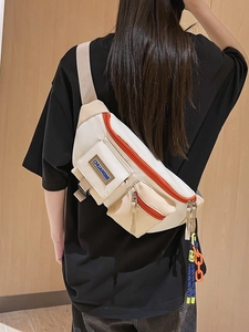 Sac de poitrine tendance en toile blanc cassé avec zip orange et accessoire décoratif