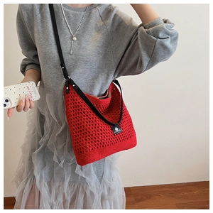 Détail du sac à bandoulière en tricot rouge avec sangle en cuir noir sur un mannequin
