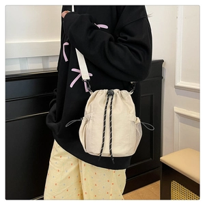 Detail der cremeweißen Kordelzug-Beuteltasche mit seitlicher Netztasche und Schultergurt