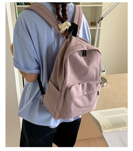 Pink minimalist backpack with front zipper pocket shown in a cozy indoor lifestyle setting
