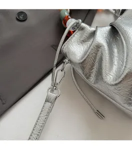Close-up of silver pleated bucket bag with metallic texture and colorful bead handle