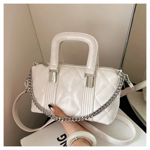 Detail of cream white quilted bag featuring silver chain strap and shiny faux leather texture