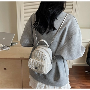 Detail of white quilted backpack with sparkling rhinestones and silver chain straps