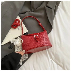 Détail du sac seau rouge tressé avec boucle argentée et charm nœud en perles