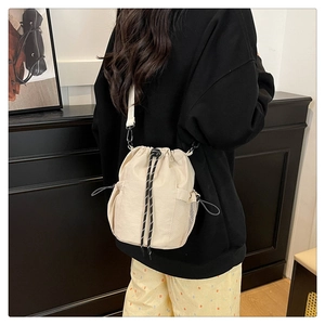 Detail der beigen Nylon-Beuteltasche mit Netzseitentasche und verstellbarem Gurtband