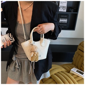 Détail du sac seau blanc tressé avec charm ours mignon et bandoulière fine amovible