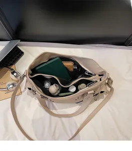 Vue intérieure du cabas beige à rivets montrant sa grande capacité et ses poches